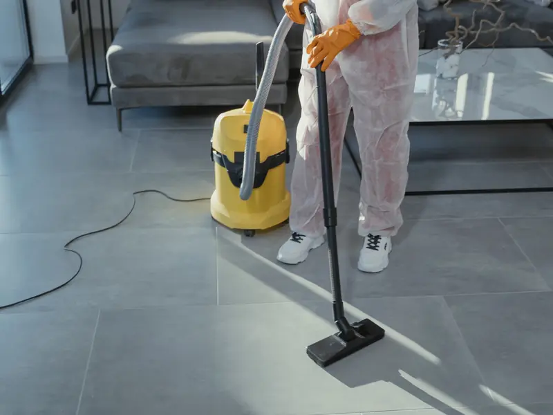 Profissional aspirando o piso de uma sala de estar moderna
