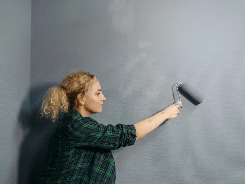 Profissional aplicando tinta em parede interna com rolo
