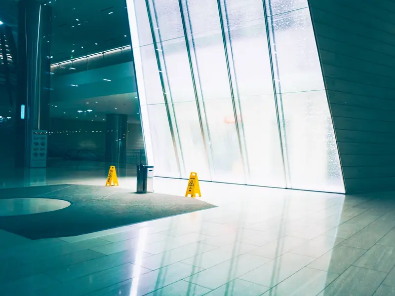 Hall de entrada de edifício com piso recém-lavado e placas de piso molhado