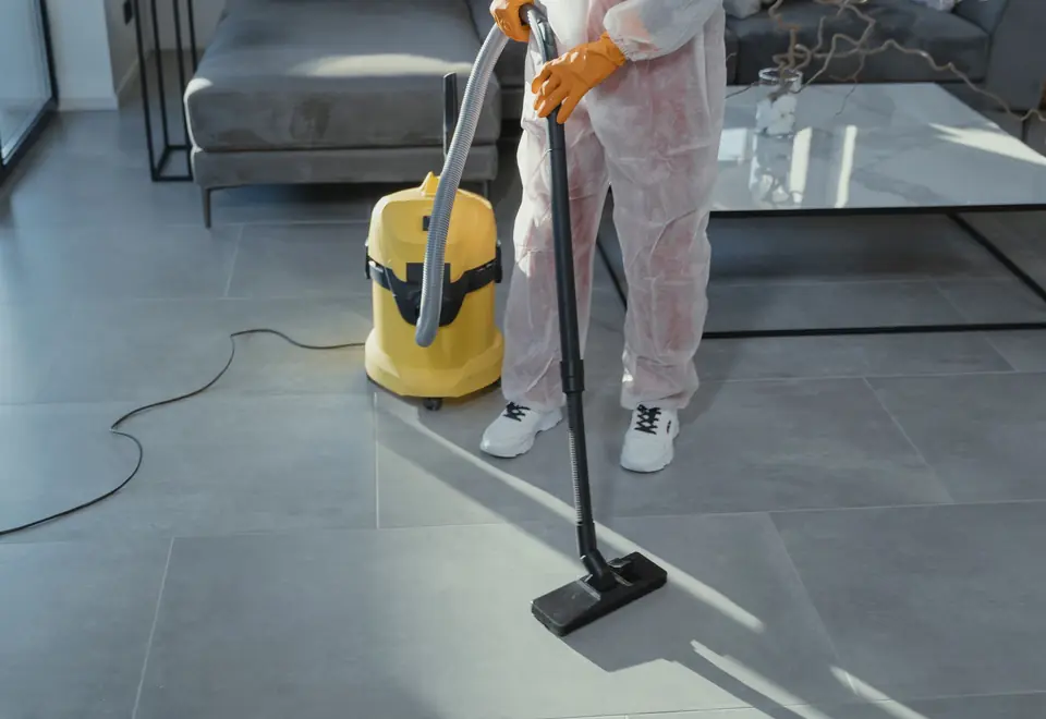 Profissional aspirando o piso de uma sala de estar moderna