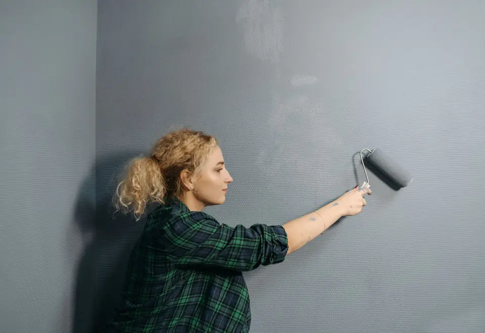 Profissional aplicando tinta em parede interna com rolo