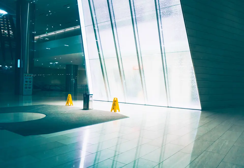 Hall de entrada de edifício com piso recém-lavado e placas de piso molhado