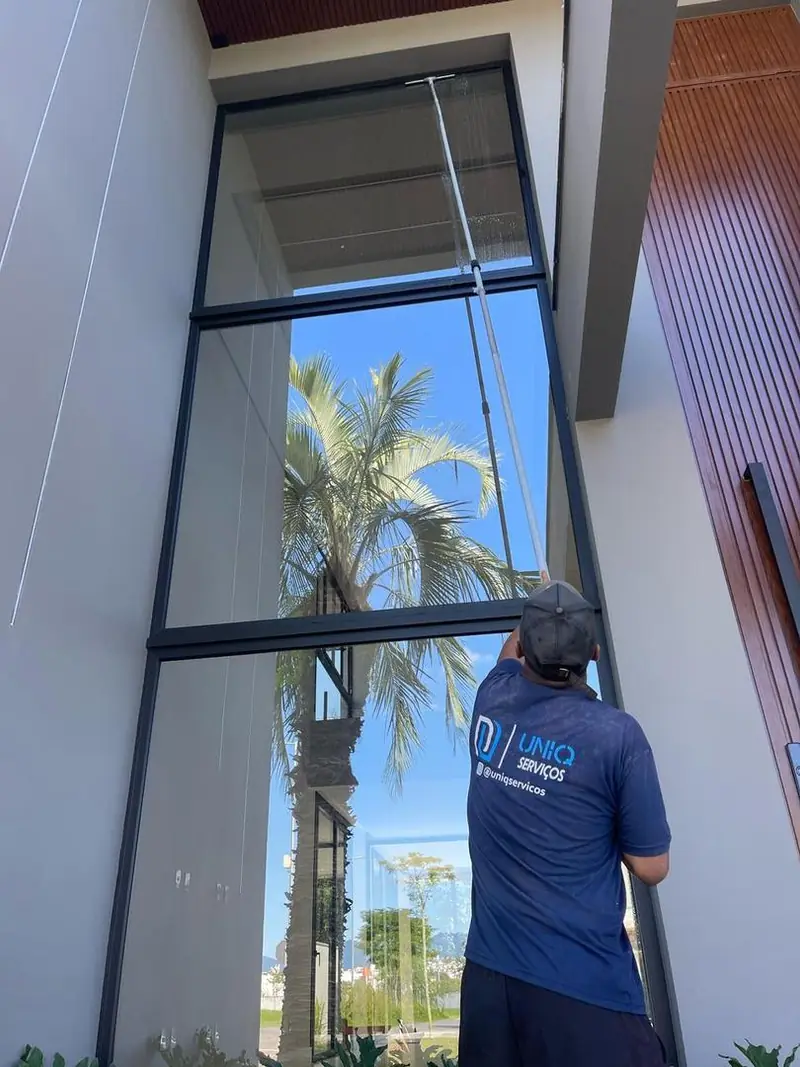 Profissional da Uniq Serviços limpando fachada de vidro com extensor
