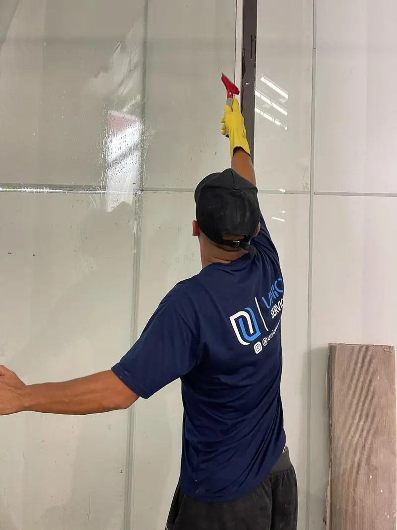 Profissional da Uniq Serviços limpando uma superfície envidraçada